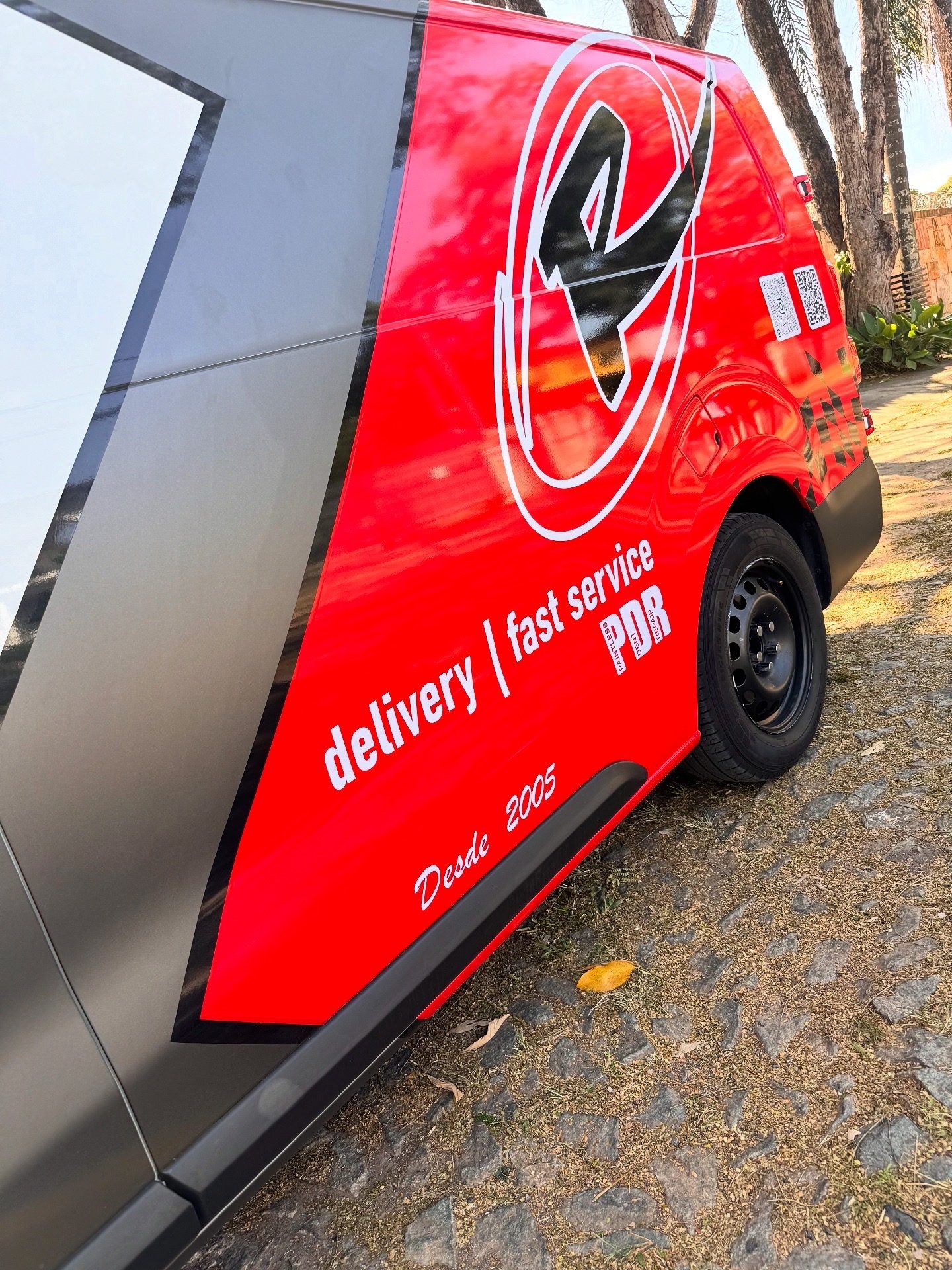 Lateral da van vermelha, com as inscrições delivery, fast service e PDR